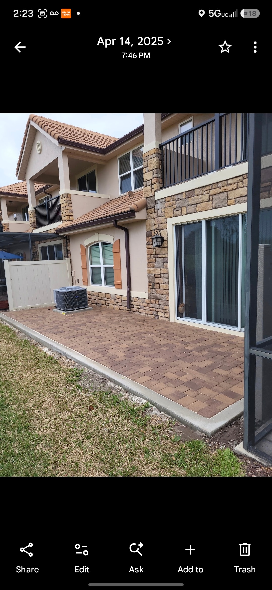 Two-story home with stone exterior and brick patio with screen enclosure