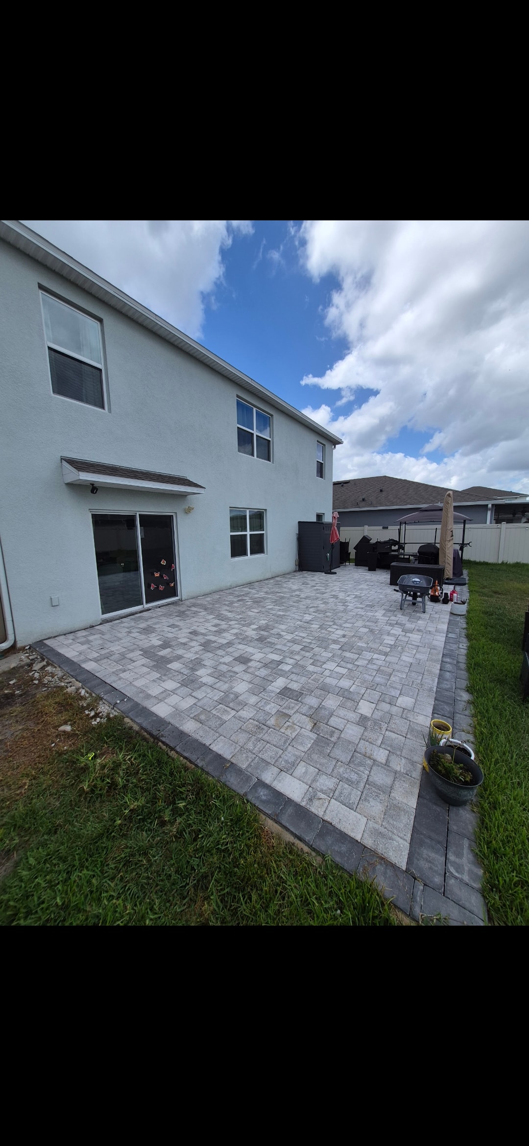 Paver patio installation on white stucco home with backyard