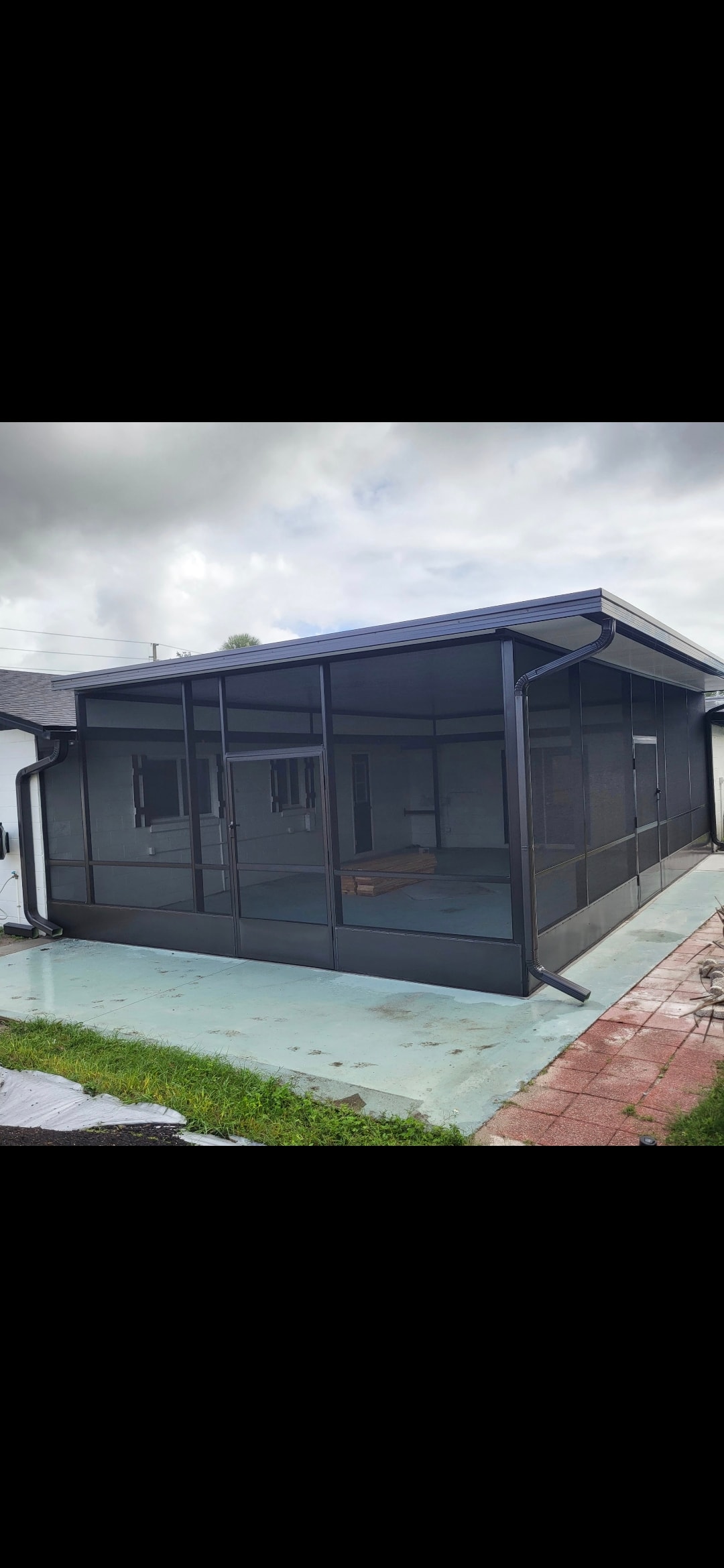 Large dark frame screen room enclosure under construction on white home