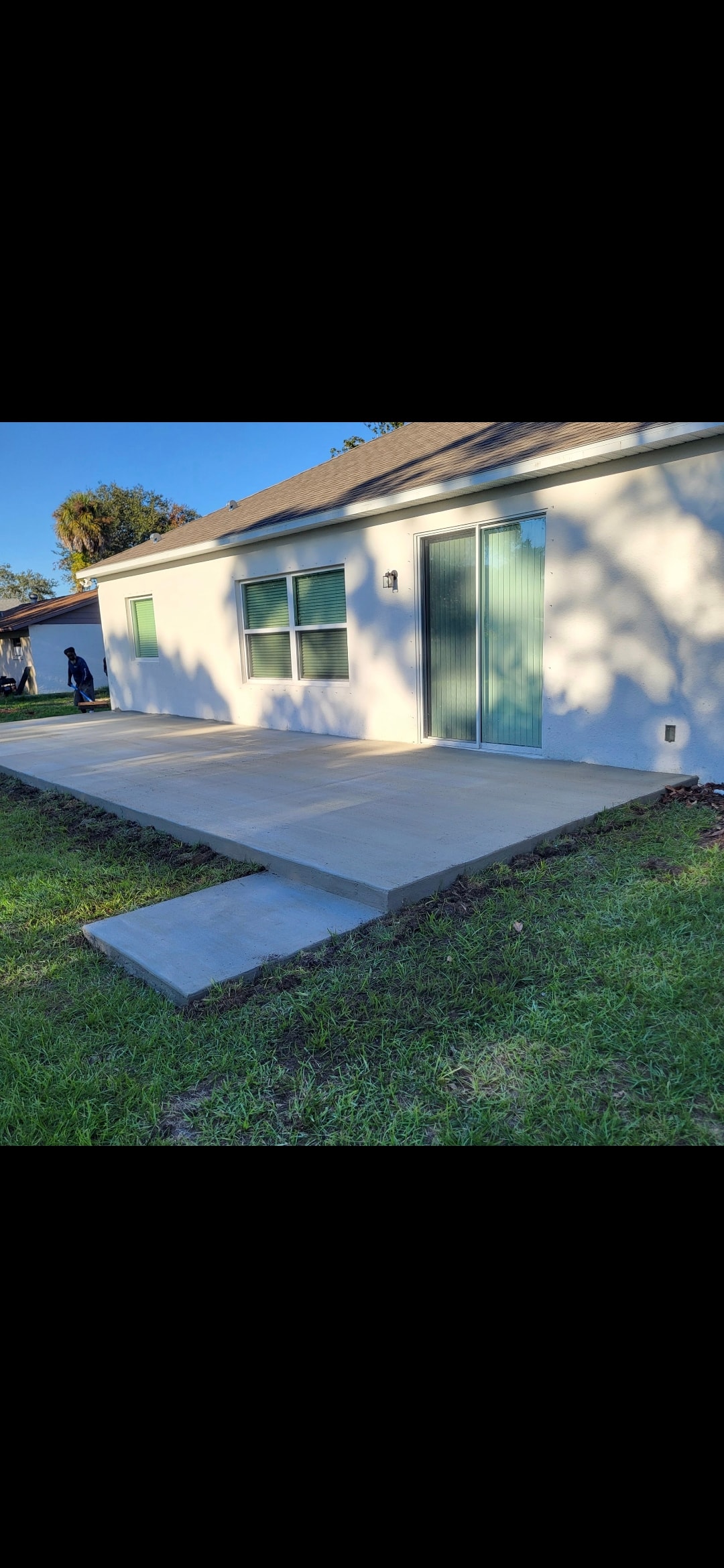 Freshly poured concrete patio slab on white stucco home