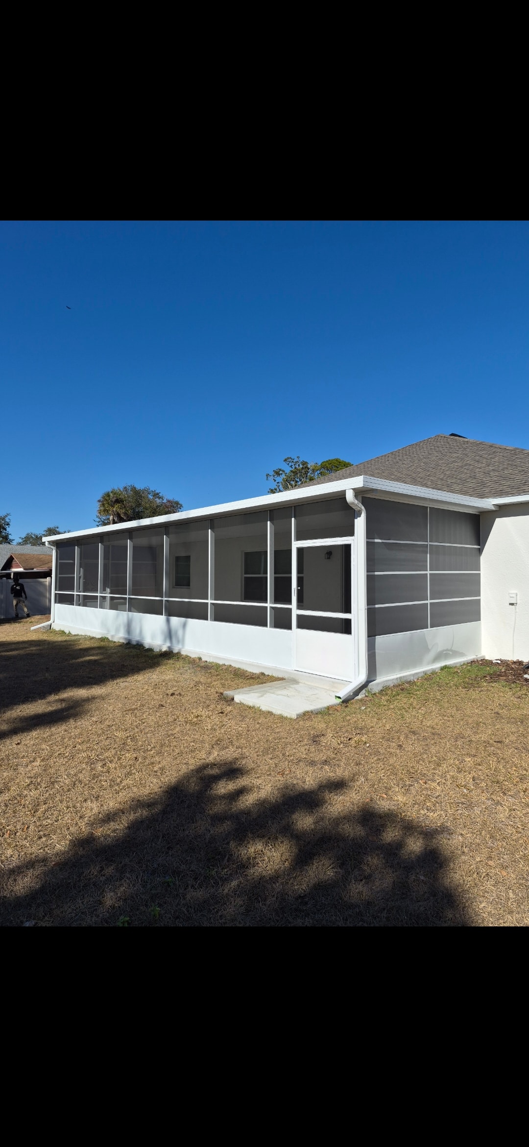White aluminum screen room enclosure on white stucco home