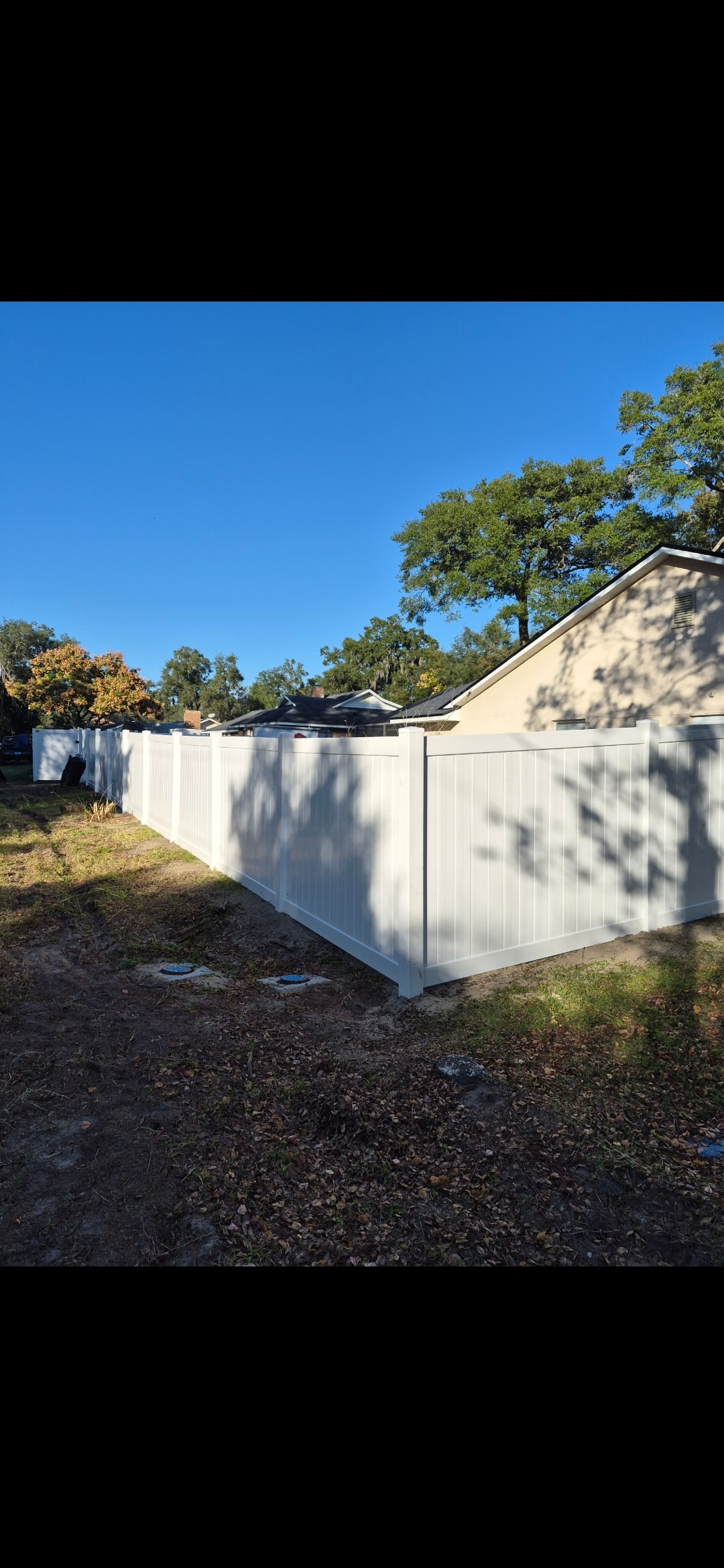 White vinyl privacy fence installation along residential yard