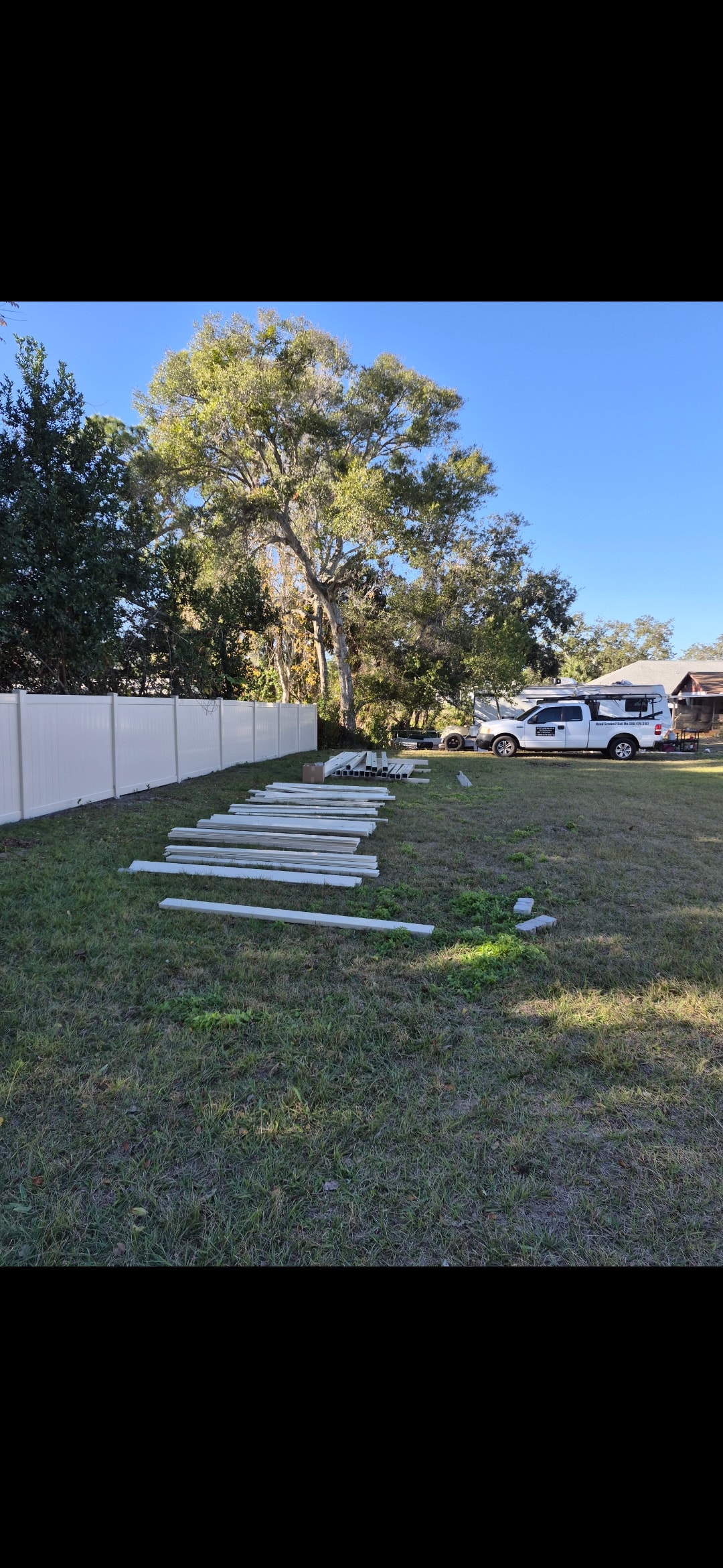 Fence materials laid out on grass before installation with work truck